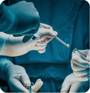 Detalhe de pinças cirúrgicas e mãos da equipa médica em cirurgia oncológica complexa.